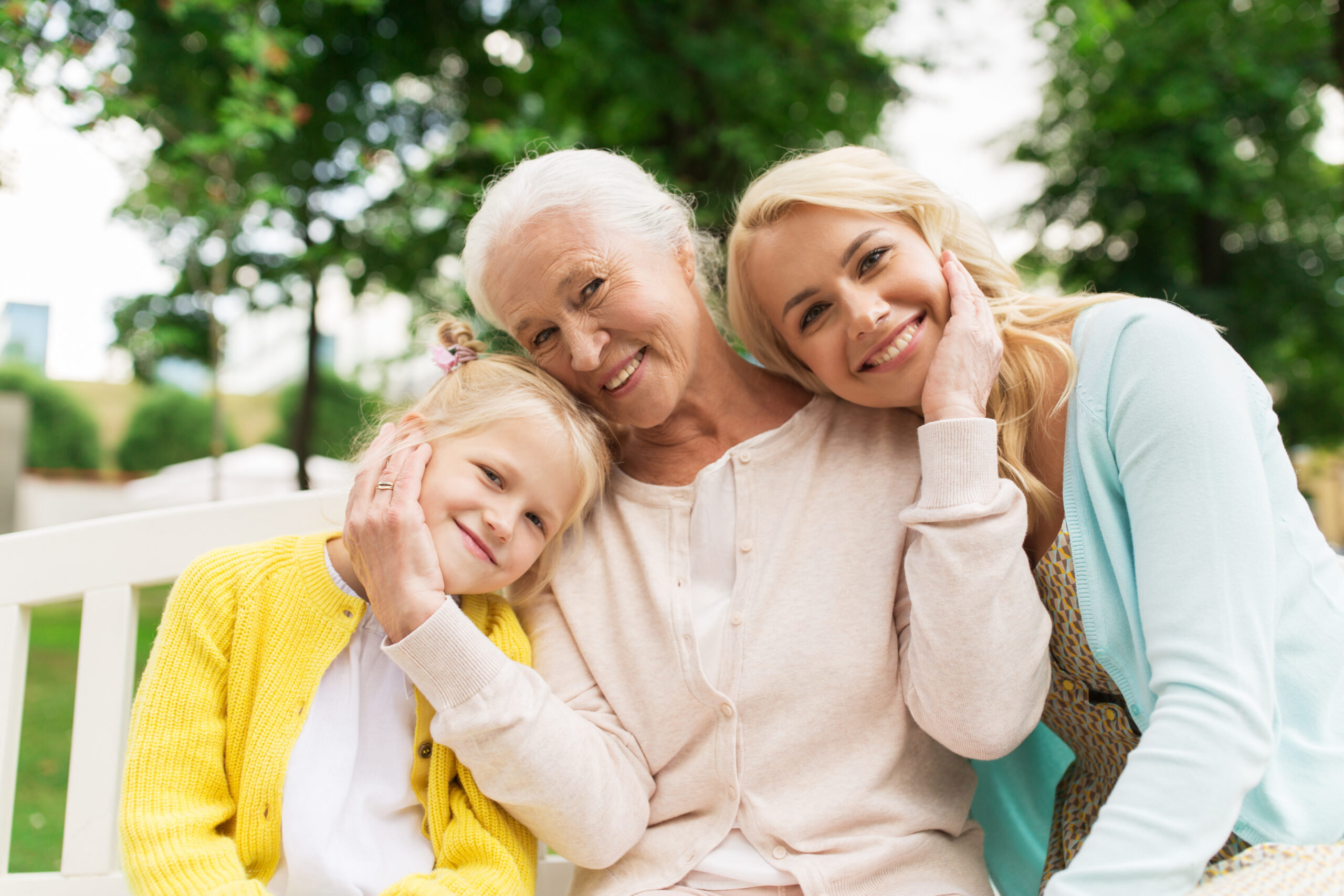 family, generation and people concept - happy smiling woman with daughter and senior mother sitting on park bench