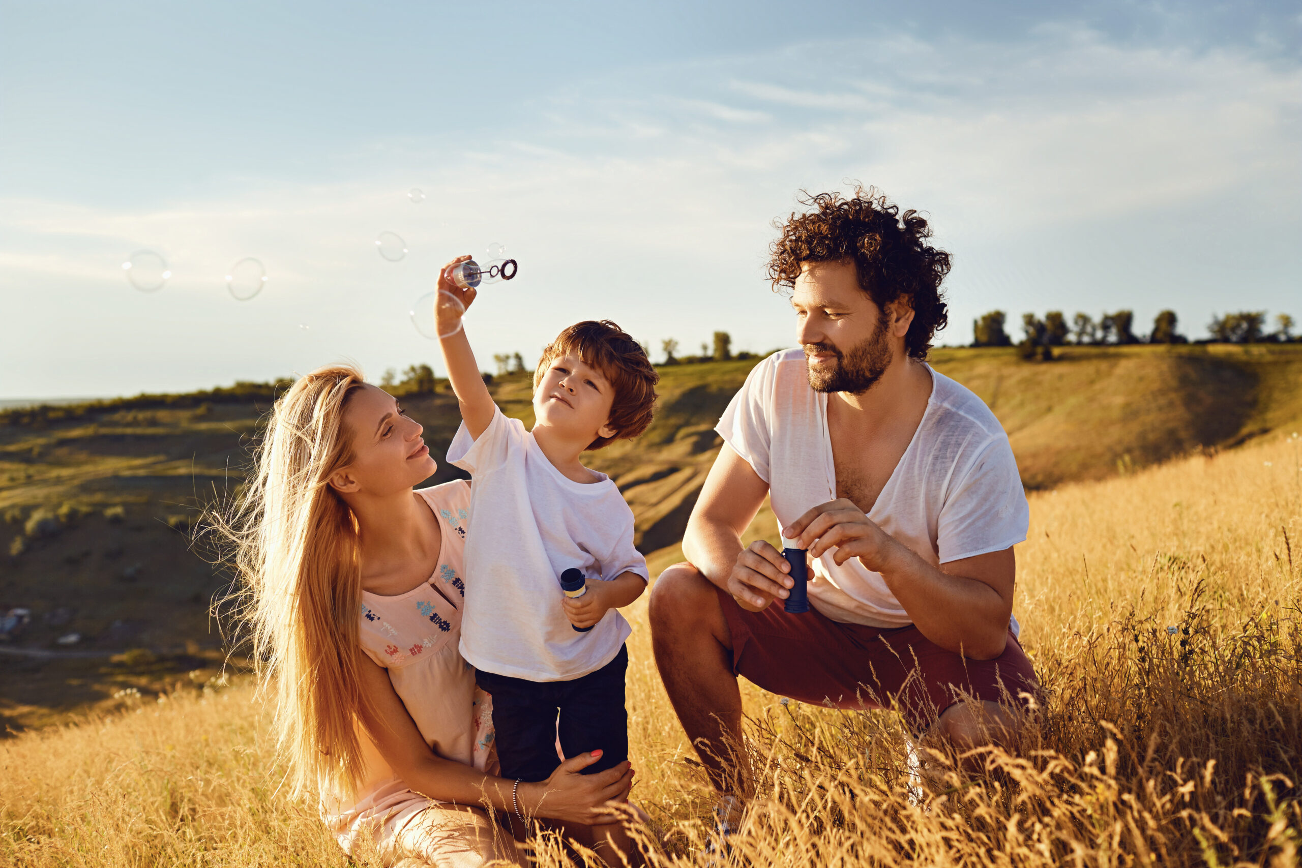 The family is playing with soap bubbles in nature.