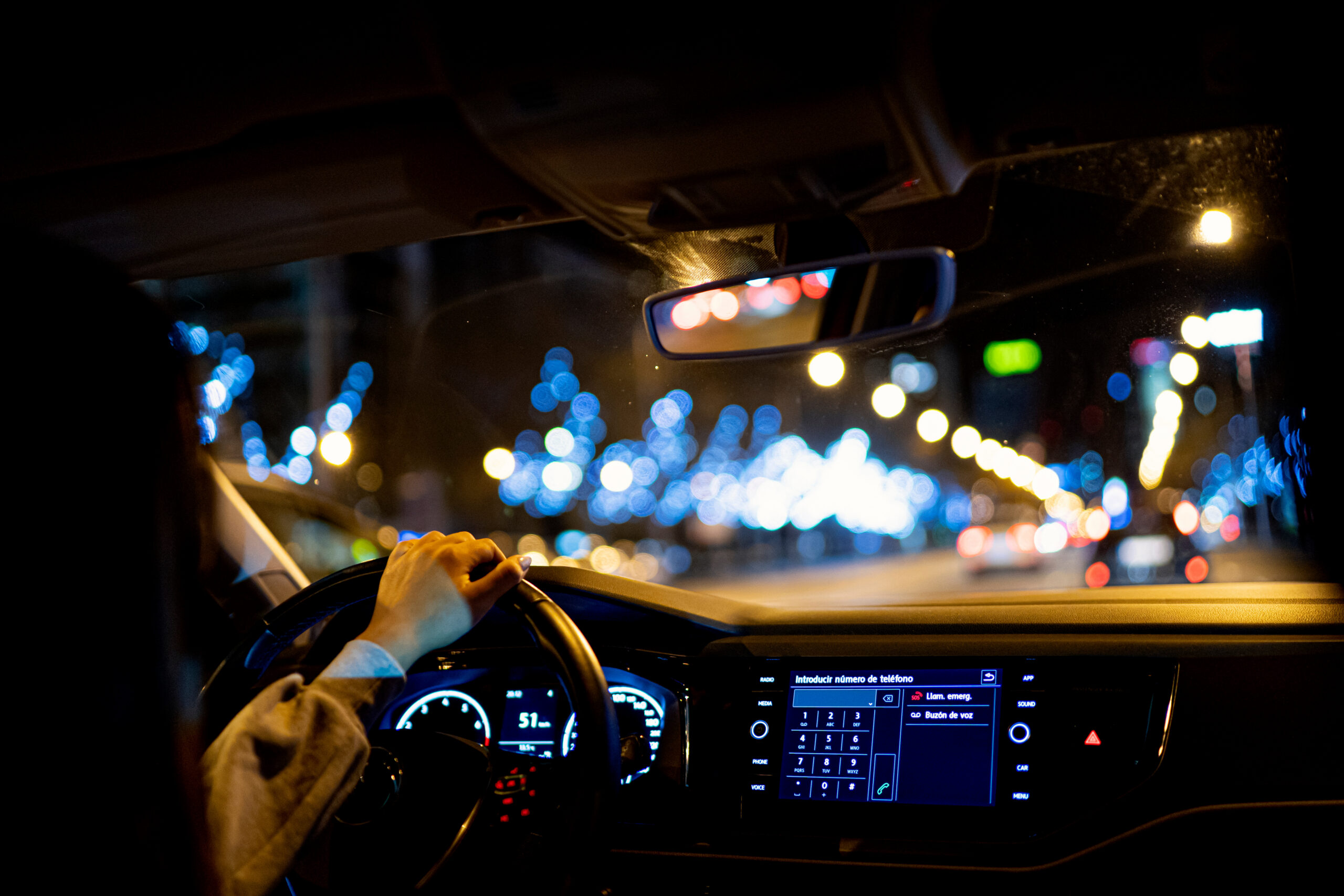 A woman driving a car at night by city.